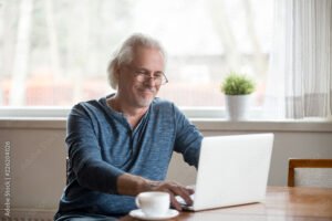 personne agee souriante travaillant sur ordinateur