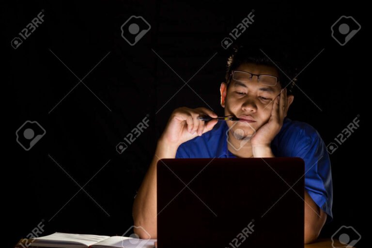 personne reflechissant devant un ordinateur sombre